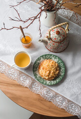 Cozy homemade morning - crumble, almond petals bun, honey, green tea on a round wooden table, top view