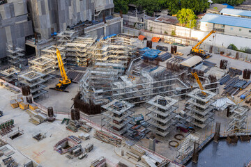 Aerial view of a large construction of a residential area with many multi-storey buildings under construction, a lot of tower cranes, workers, construction equipment at sunset
