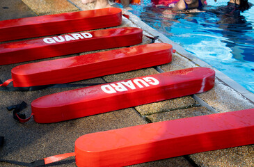 Selective focus shot of a red Plastic guards beside the swimming pool. Floating block for kids swimming training course use. 