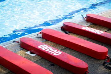 Selective focus shot of a red Plastic guards beside the swimming pool. Floating block for kids swimming training course use. 
