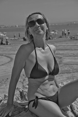 Portrait of woman wearing bikini while sitting at beach against sky