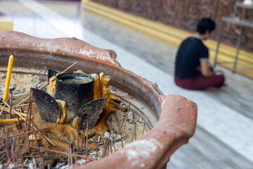 Extinguished candles and incense sticks in a container in a Buddhist temple where worshipers pray