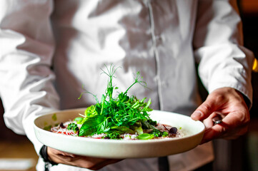 chef hand hold plate Fresh healthy tomato carpaccio with balsamic vinegar, cheese and salad