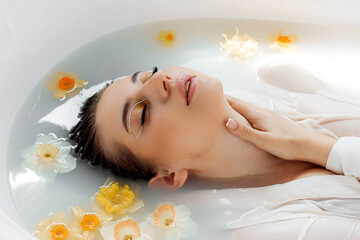 Obraz na płótnie Canvas the face of a girl in a milk bath with flowers