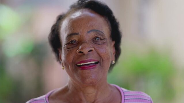 One happy black senior Brazilian woman close-up face smiling at camera standing outside. Portrait of a joyful African American lady