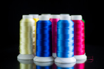 set of different color sewing threads,on black background.