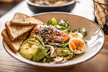 Healthy leaf salad prepared with avocado, eggs, sesame and grilled salmon