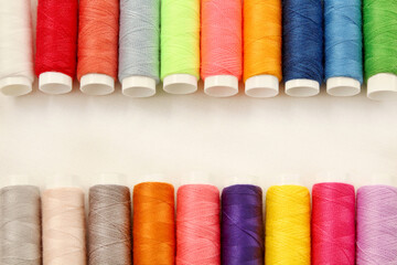 Spool of sewing threads multicolored on white cotton fabric with copy space for design art work.