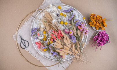 Farbenfrohe Trockenblumen auf einem Teller, getrocknete Blumen wie Lagurus, Strandflieder, Hirse, Craspedia, Pampasgras, Phalaris und Strohblumen
