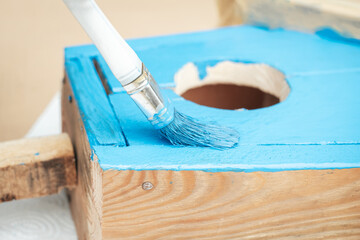 Closeup to a paint brush with blue color. Oil painting on DIY bird house.