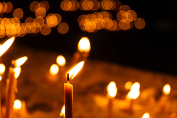 A lot of burning candles in the temple in the dark. The concept of religion, prayer and God.