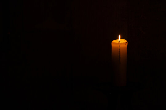 A lonely burning candle in an old temple against the background of a wall, a place for text
