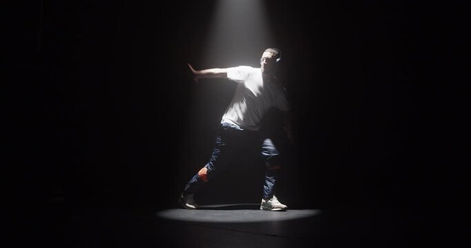 Active talented man dancing breakdance in dark studio