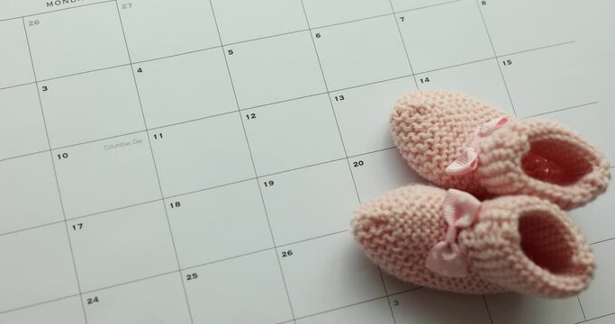 Selected due date on calendar and details of baby pink shoes. Planning for birth of child