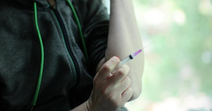 Drug addict injects heroin or drug into vein using injection needle. Drug addiction and depression