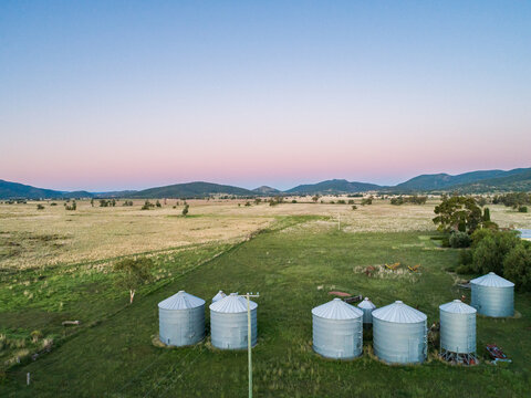 Dusk light over hills with farm silos in foreground aerial drone view
