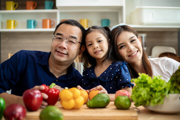 Young Asian family are preparing vegetables for the breakfast, fruits chili on table in the kitchen which Excited smiling and felling happy time.