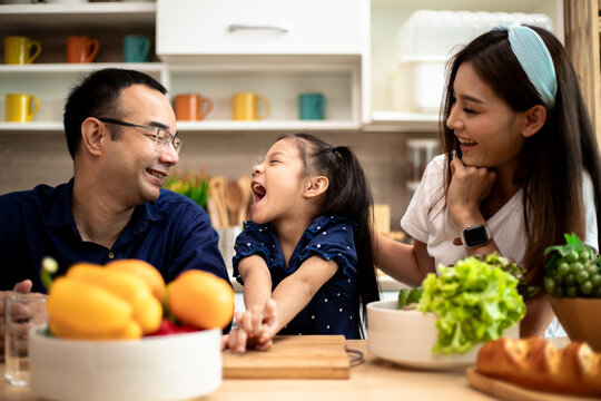 Young Asian family are preparing vegetables for the breakfast, fruits chili on table in the kitchen which Excited smiling and felling funny.