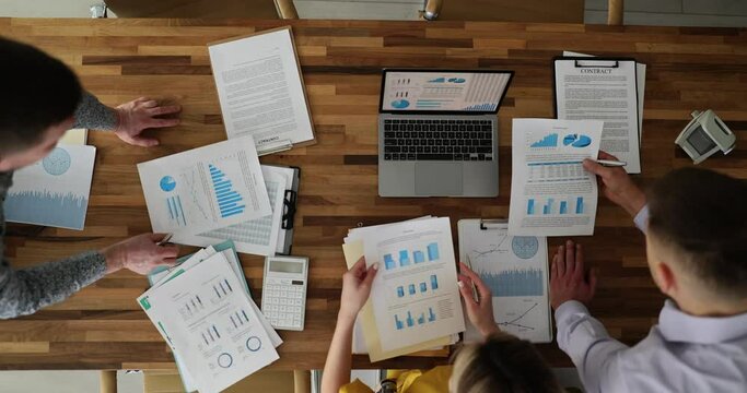 Business people discuss financial report in charts and graphs top view. Business partners analyze overall sales statistics presenting deals on group meeting concept
