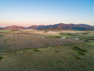 Long shadowed landscape and dusk light on distant hills over pastoral land