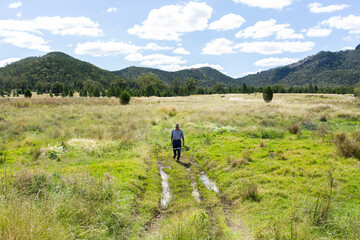 Farmer checking to see if creek crossing is passable in paddock