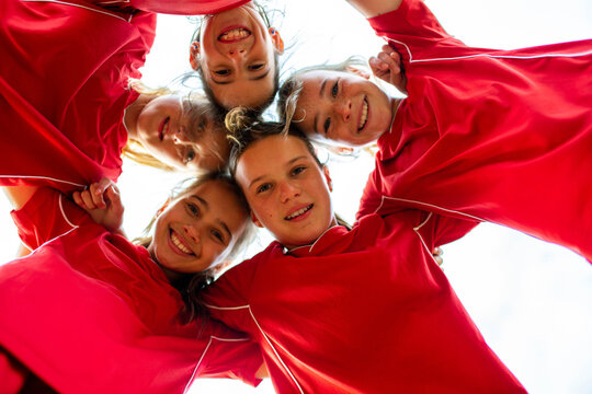 A looking up view of tween girls football team in a huddle