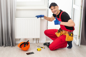 plumber at work. Installing water heating radiator