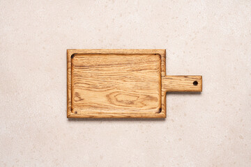Fototapeta premium Wooden cutting board on beige light concrete background, top view