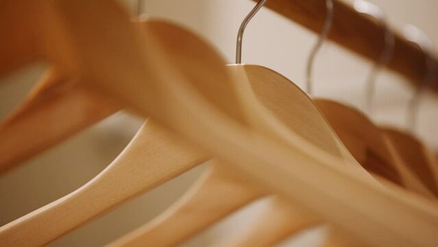 Empty wooden clothing hangers hanging on metal rack close up view. Shopping and discount concept.