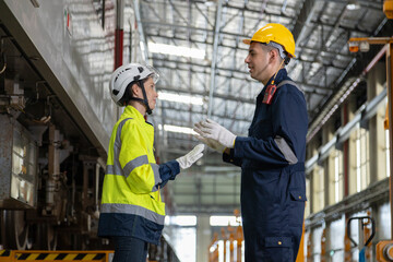 Two professional engineers checkmechanical check undercarriage of lifted electric train and maintenance of public transport trains in Asia