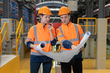 Two engineers check the spare parts list from drawing, tablet and maintenance of public transport trains in Asia