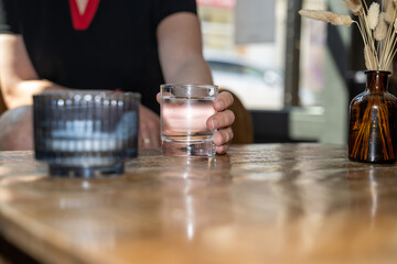 verre d'eau dans la main d'une femme sur une table de restaurant