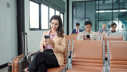 The passengers, tourist using smartphone while sitting on chair in terminal hall waiting flight in...