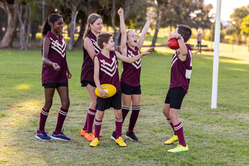 group of school kids in football team cheering each other