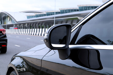 side mirror or wing mirror of a nice design black car drived on the  road in front of the train...