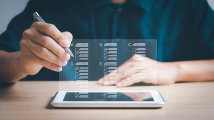 Male hand holding a pen Choose the correct answer in online test with virtual screen on tablet, online survey filling concept , filling out forms and taking online exams