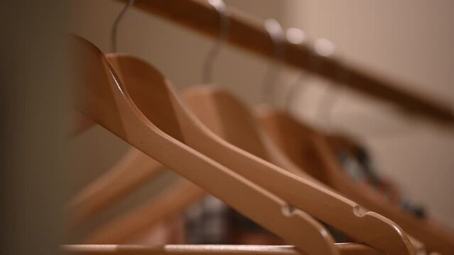 Empty wooden clothing hangers hanging on metal rack close up view. Shopping and discount concept.
