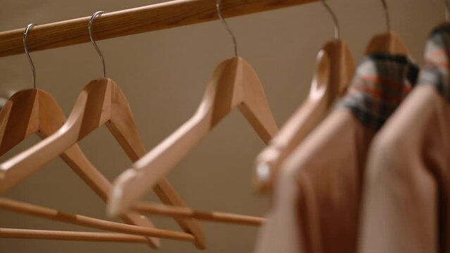 Empty wooden clothing hangers hanging on metal rack close up view. Shopping and discount concept.