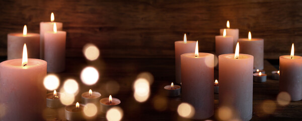Candle lights with blurred bright bokeh on dark wood for religious rituals and spiritual zen meditation or funeral ceremonies.