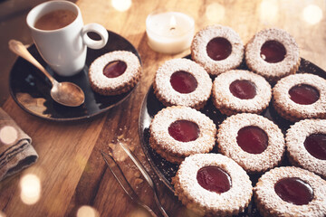 Coffee time with linzer cookies and bright bokeh on wooden table.