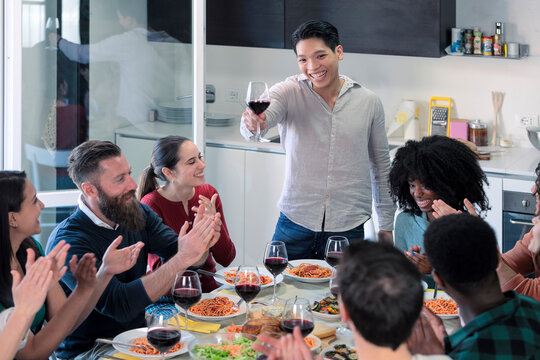 Young friends toast together to celebrate the young Asian man, friends drink wine and eat italian food
