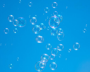 Soap bubbles in the blue sky. Beautifully iridescent balls of soap foam in the air