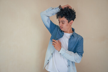 Young curly man with denim clothes wear perfume. Smile, cheers and happy expression. The photo is...