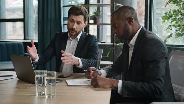 Caucasian manager showing African boss bad business result computer mistake two diverse men multiracial coworkers businessmen with papers and laptop sad upset failure discuss startup problem at office