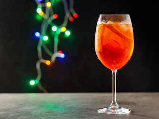 Glass of Aperol Spritz cocktail on a blurred background with colorful lights. Aperol spritz...