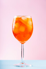 Aperol Spritz cocktail in glass on a pink blue background. Cocktail Aperol Spritz with orange and ice cubes. Close up