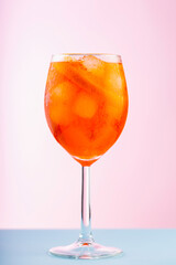 Aperol Spritz cocktail in glass on a pink blue background. Cocktail Aperol Spritz with orange and ice cubes. Close up