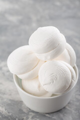 Marshmallows in bowl on a gray background. Sweet dessert zephyr marshmallows on concrete. Close up