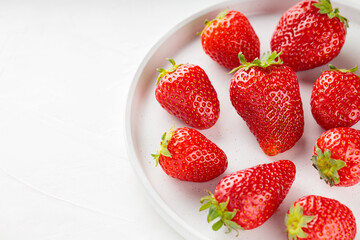Ripe strawberries on white plate. Fresh delicious strawberries on white background. Top view. Copy space