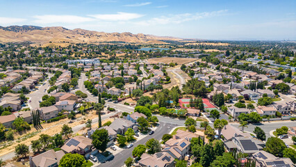 Aerial images over a community in Antioch, California with houses, cars, streets and trees. With a...